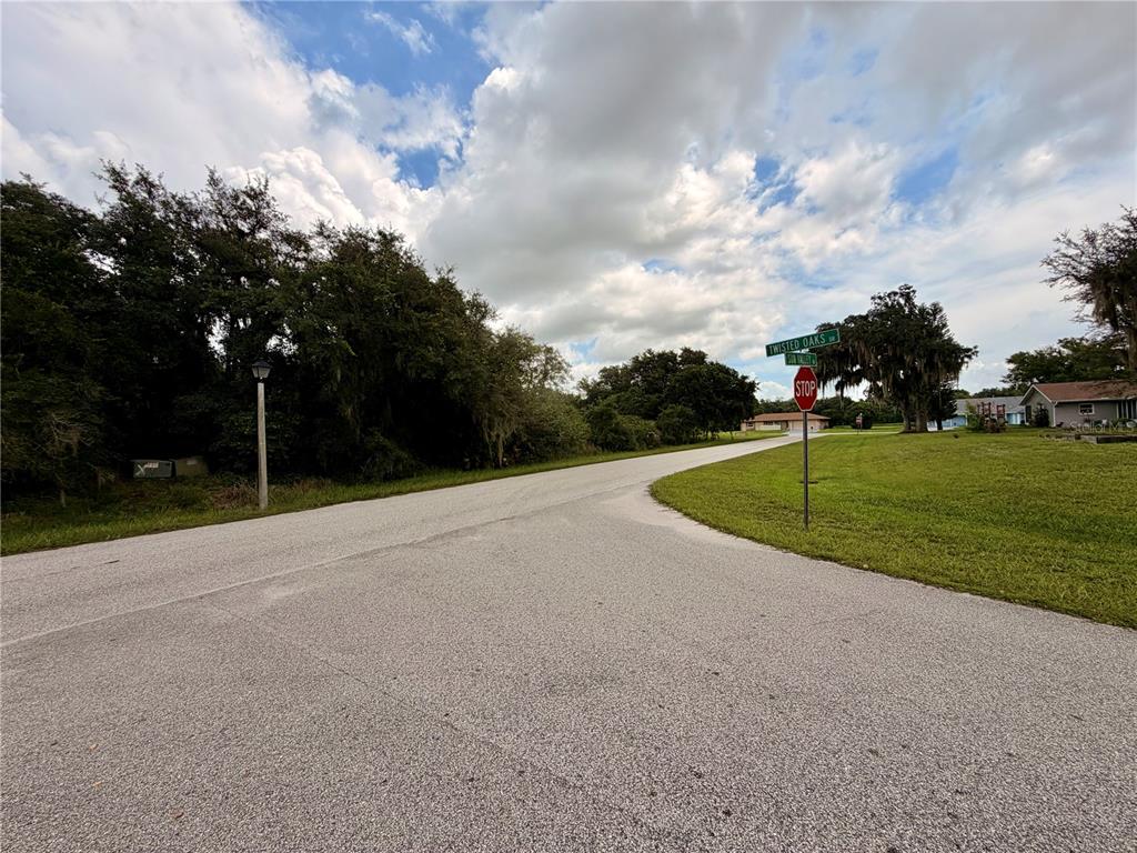 A paved road intersection features a stop sign and street signs under a cloudy sky — 5709 SUN VALLEY DRIVE, SEBRING, FL