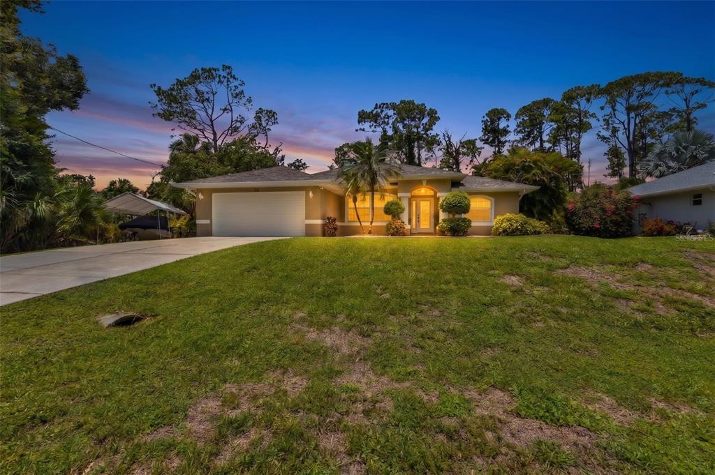 A single-story house with a two-car garage and a large front lawn at dusk — 131 SUNDIET STREET, PORT CHARLOTTE, FL