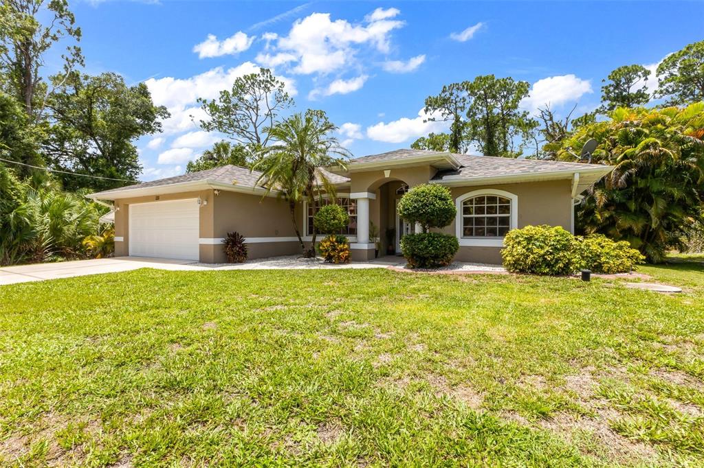 A single-story house with a white garage, tan stucco exterior, and a landscaped front yard — 131 SUNDIET STREET, PORT CHARLOTTE, FL