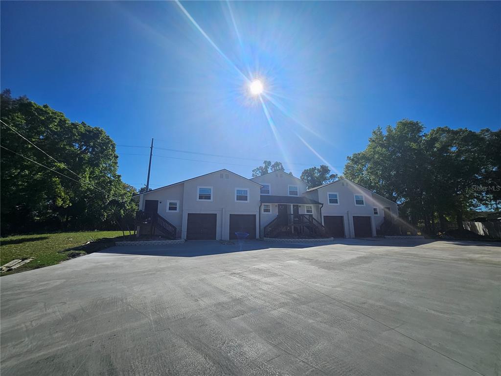 A multi-unit residential building with garages and a large concrete driveway under a bright sun — 5802 MOHR LOOP UNIT 5802 5804 5806 5808, TAMPA, FL