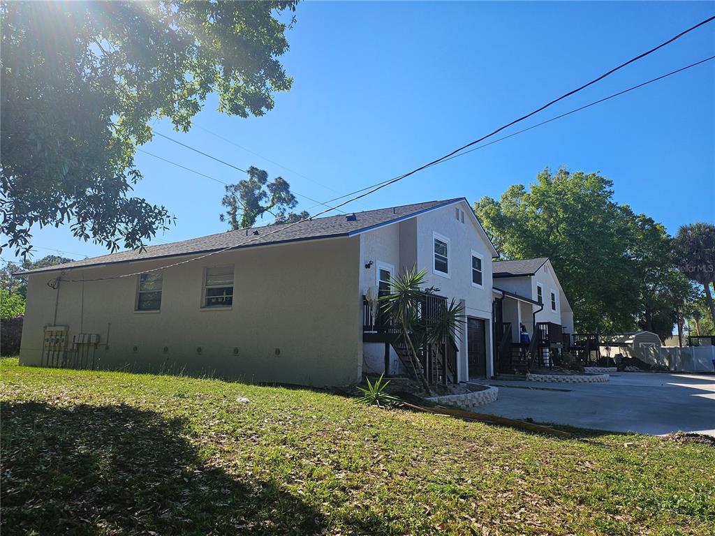 A side view of a two-story tan building with a concrete driveway and trees — 5802 MOHR LOOP UNIT 5802 5804 5806 5808, TAMPA, FL