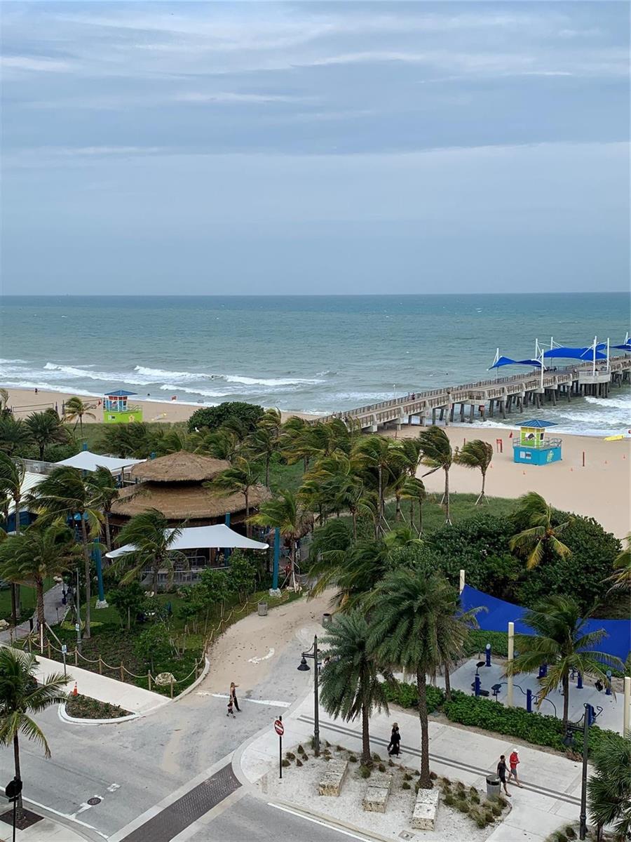An elevated view of a beach with a pier, palm trees, and a lifeguard tower — 133 N Pompano Beach Boulevard # 808, Pompano Beach FL 33062, POMPANO BEACH, FL