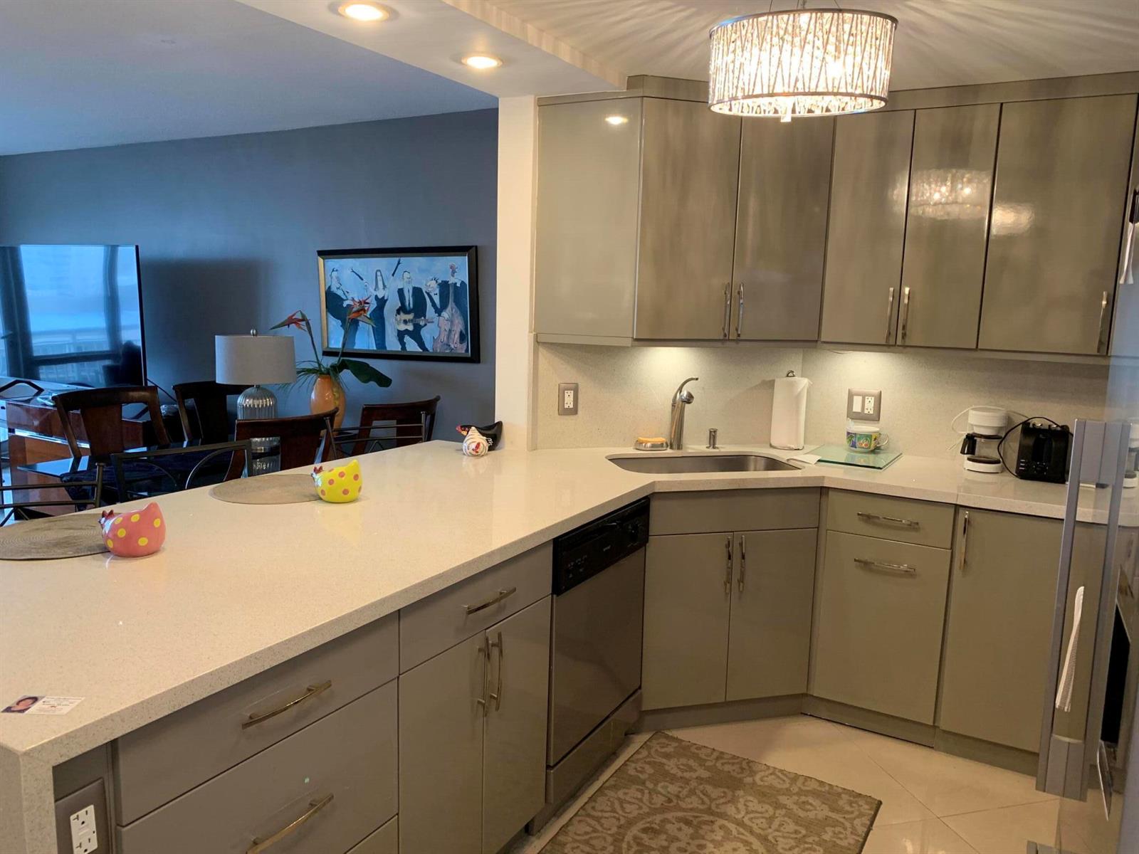 A kitchen with grey cabinets, white countertops, and a peninsula overlooking a dining area — 133 N Pompano Beach Boulevard # 808, Pompano Beach FL 33062, POMPANO BEACH, FL