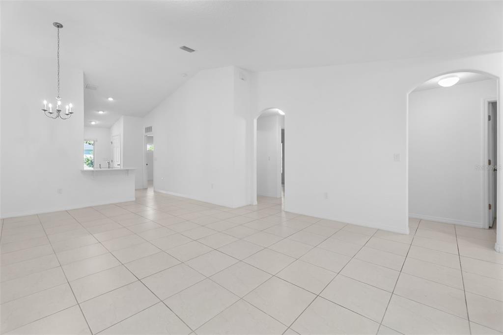 An open-concept living area features white walls, vaulted ceilings, and light-colored tile flooring — 10 PONTIAC LANE, PALM COAST, FL