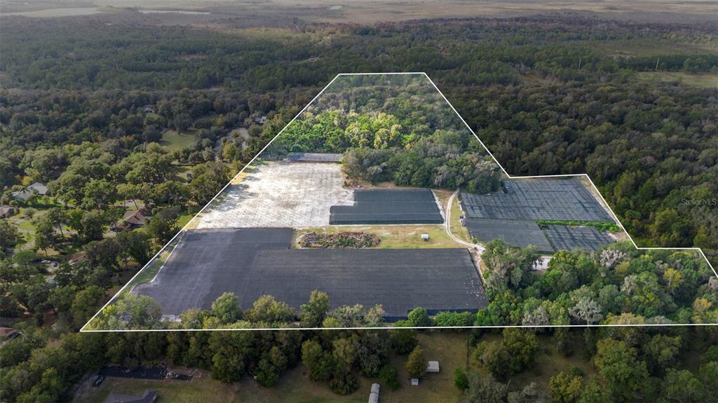 An aerial view shows a large plot of land with several agricultural shade structures — KING STREET, DELAND, FL