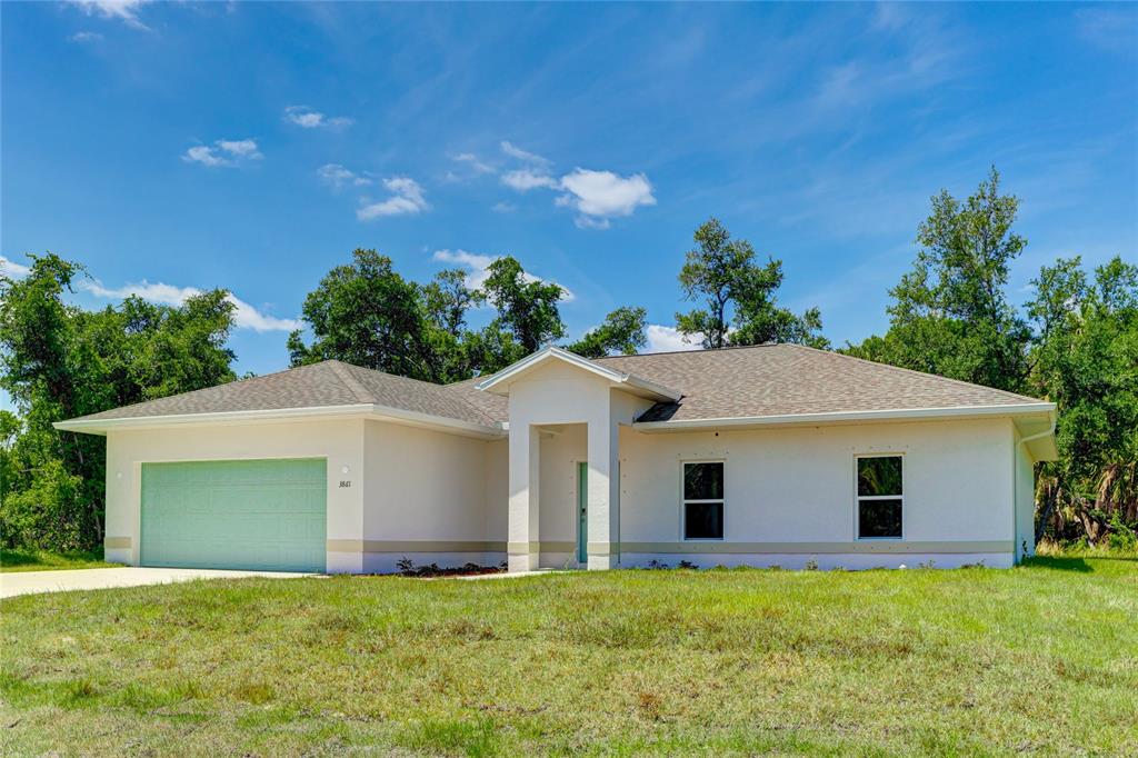 A single-story house with a light-colored stucco exterior, a two-car garage, and a shingled roof — 3861 URIAH STREET, NORTH PORT, FL