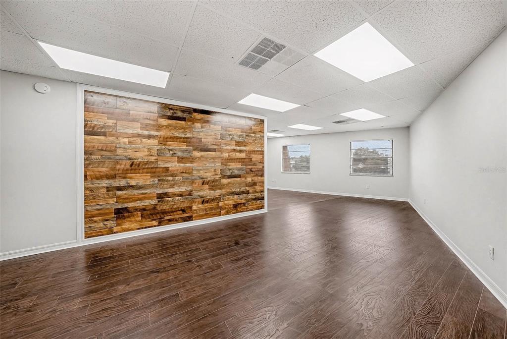 An empty office space features a wood-paneled accent wall and dark wood-look flooring — 4435 GUNN HIGHWAY, TAMPA, FL