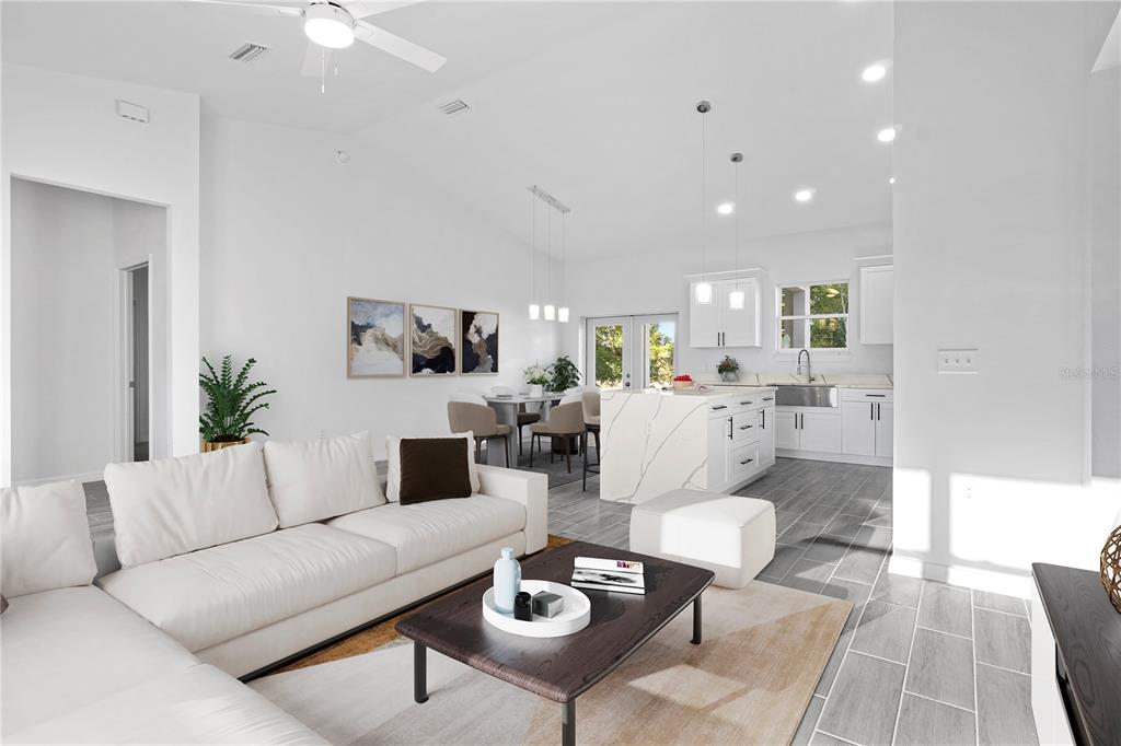A bright, open-concept living room and kitchen featuring white cabinetry, marble-topped island, and tile flooring — 42 JUNIPER PASS TERRACE, OCALA, FL