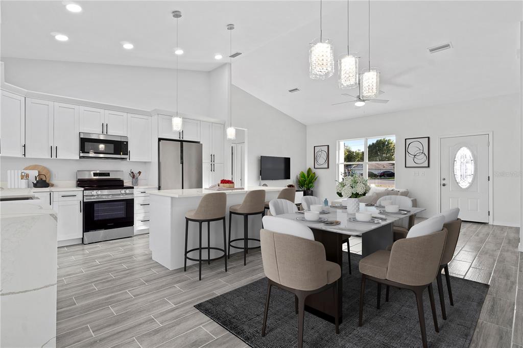 A modern open-concept kitchen and dining area features white cabinetry, stainless appliances, and tile flooring — 42 JUNIPER PASS TERRACE, OCALA, FL