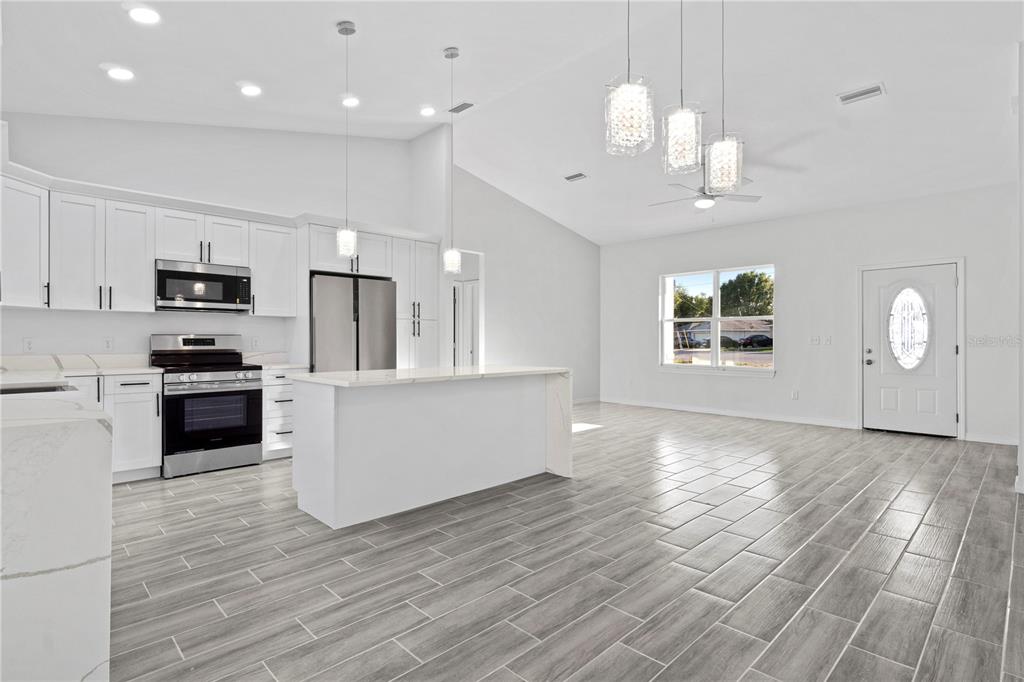 A modern kitchen with white cabinets, stainless steel appliances, and a central island — 42 JUNIPER PASS TERRACE, OCALA, FL