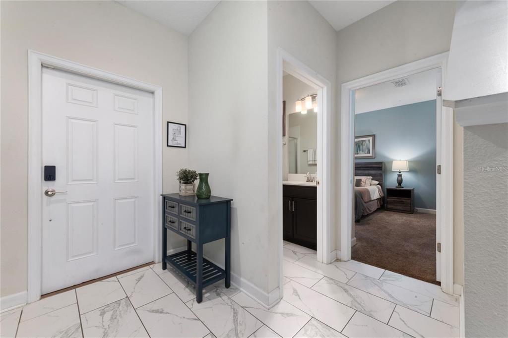 A white front door opens into a tiled entryway with a small blue console table — 8930 STINGER DRIVE, DAVENPORT, FL