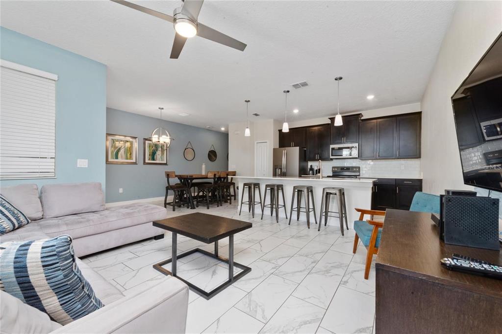 An open-concept living room and kitchen with white tile floors and dark wood cabinetry — 8930 STINGER DRIVE, DAVENPORT, FL