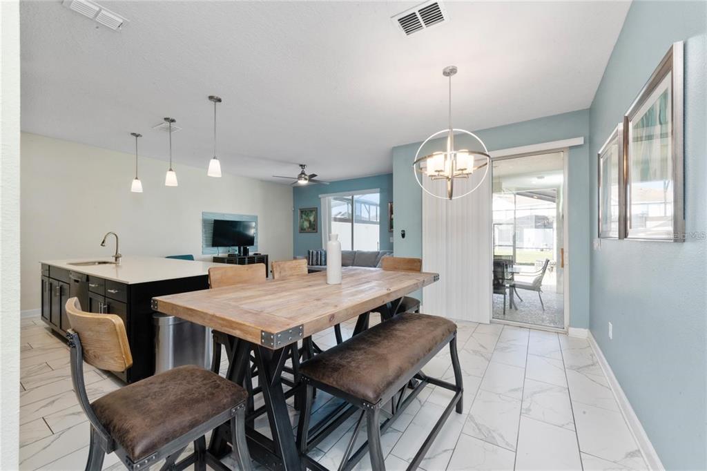 A dining area with a wooden table and benches sits next to a kitchen island — 8930 STINGER DRIVE, DAVENPORT, FL