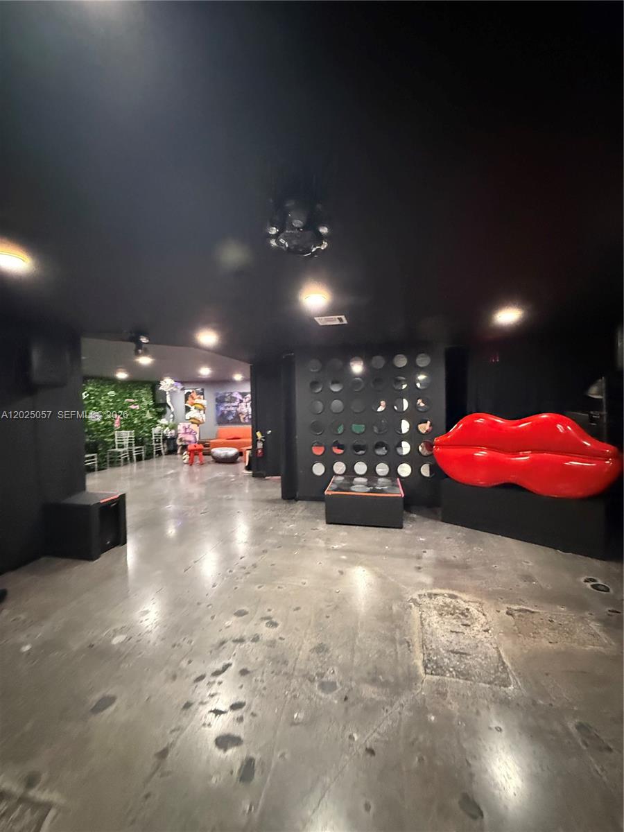 A dark, open-concept room features a large red lip sculpture and a circular-patterned accent wall — 777 NE 79th St, Miami FL 33138, MIAMI, FL