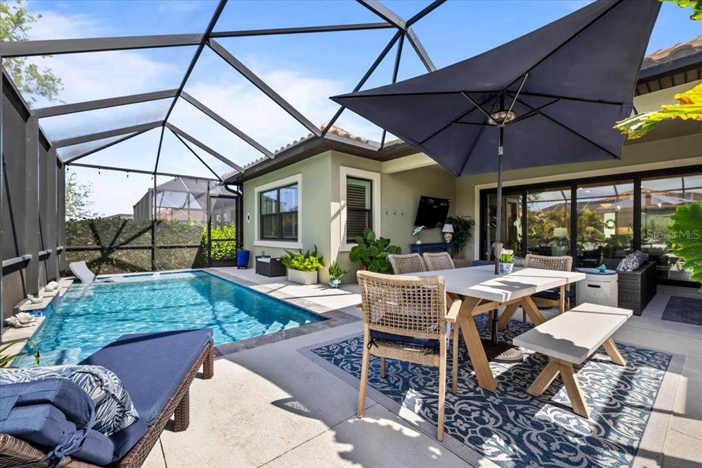 A screened-in patio features a swimming pool, outdoor dining set, and a large umbrella — 2214 5TH STREET E, PALMETTO, FL