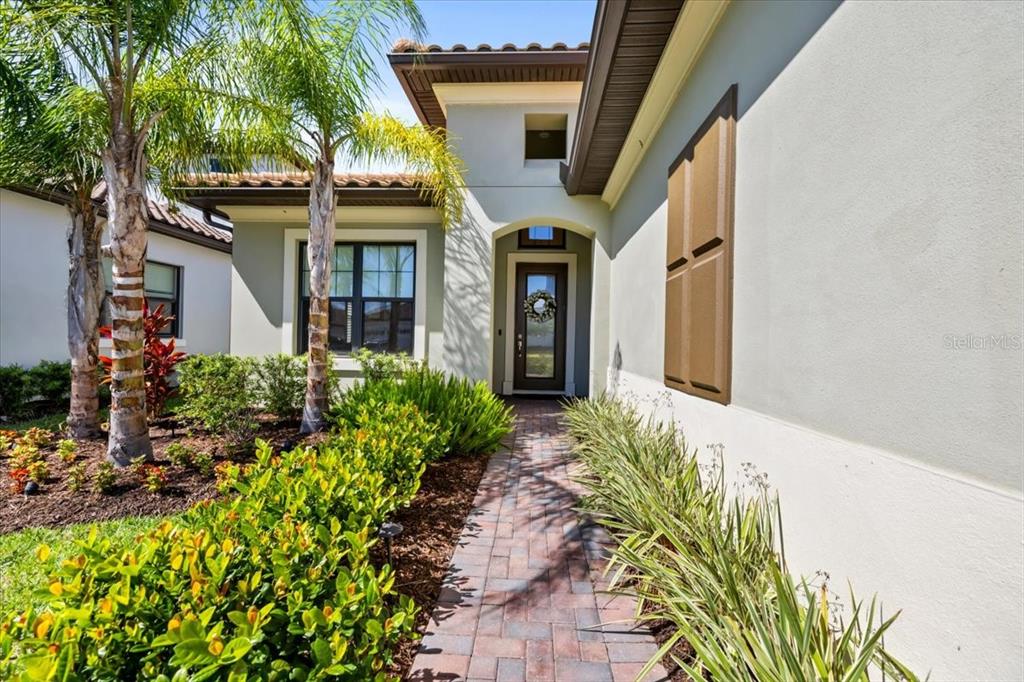 A paved walkway leads to the front entrance of a house with palm trees — 2214 5TH STREET E, PALMETTO, FL