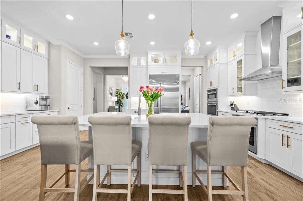 A bright kitchen features white cabinetry, a large central island with seating, and stainless appliances — 2214 5TH STREET E, PALMETTO, FL