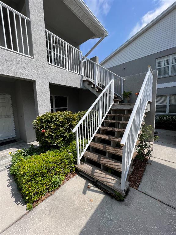 An exterior view of a multi-story building featuring a wooden staircase with white railings — 9485 HAMLIN BOULEVARD UNIT 8, SEMINOLE, FL