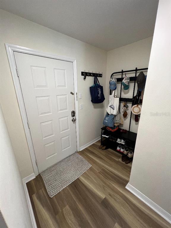 An entryway features a white door, a wall-mounted coat rack, and a metal shoe storage unit — 9485 HAMLIN BOULEVARD UNIT 8, SEMINOLE, FL