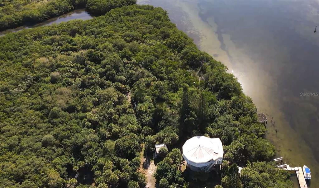 An aerial view shows a circular house nestled in dense trees along a waterfront — 10049 HEL-LEW COURT, PLACIDA, FL
