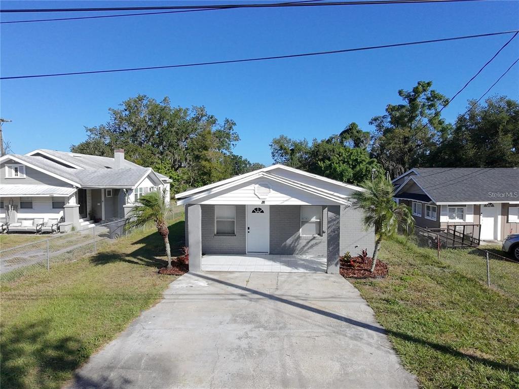 A single-story gray brick house features a front porch, a concrete driveway, and two palm trees — 2408 E MAGNOLIA STREET, LAKELAND, FL