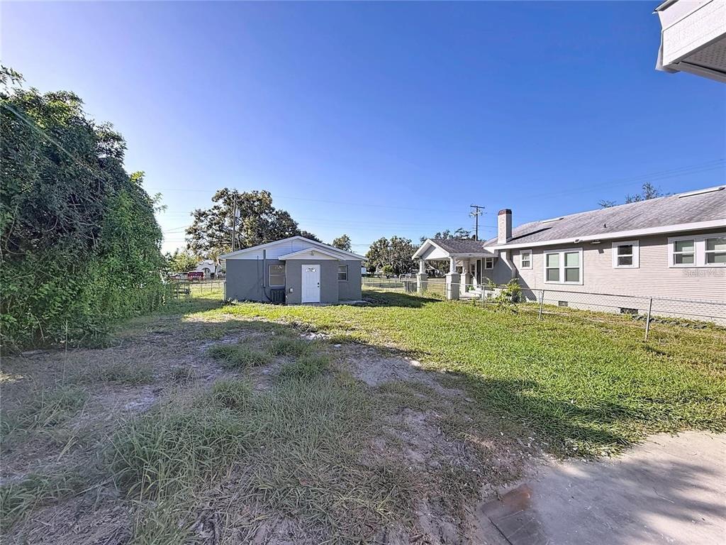 A backyard view showing a detached garage, a house with a porch, and grass — 2408 E MAGNOLIA STREET, LAKELAND, FL