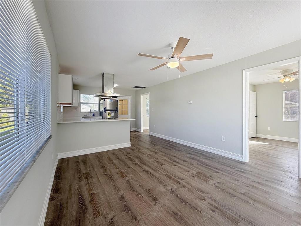 A bright living area with wood-look flooring, a ceiling fan, and an open kitchen — 2408 E MAGNOLIA STREET, LAKELAND, FL