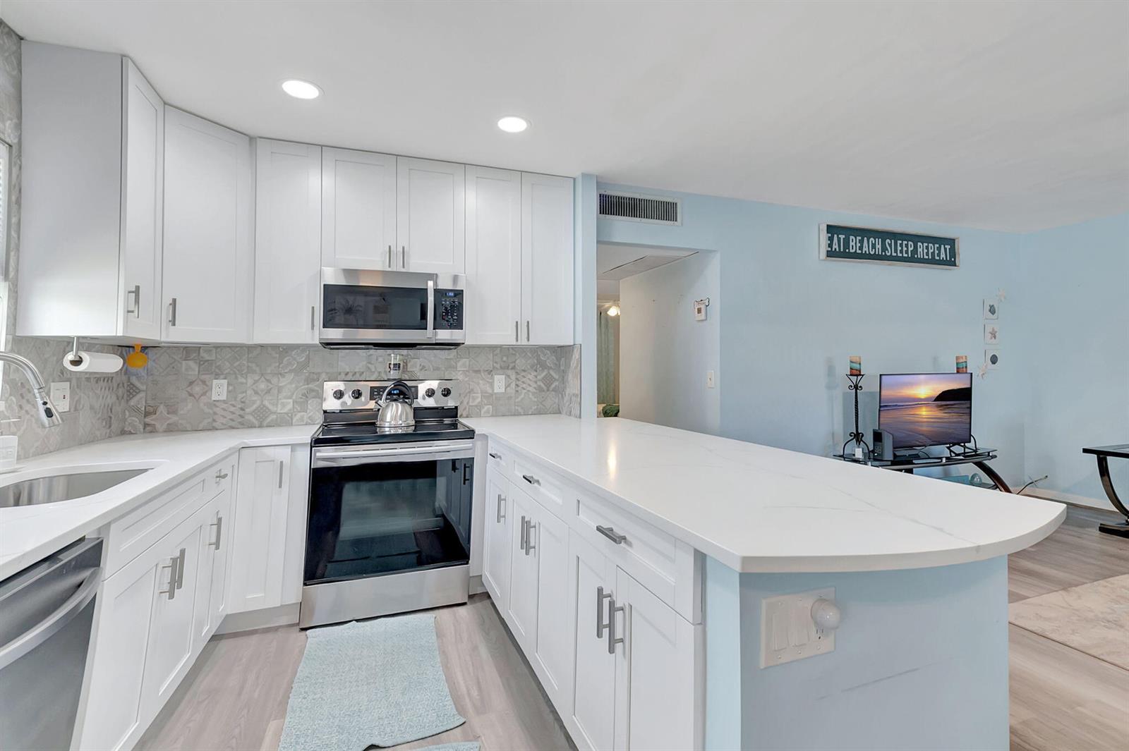 A kitchen with white cabinets, stainless steel appliances, and a peninsula counter in a home — 89 Flanders Way # B, Delray Beach FL 33484, DELRAY BEACH, FL