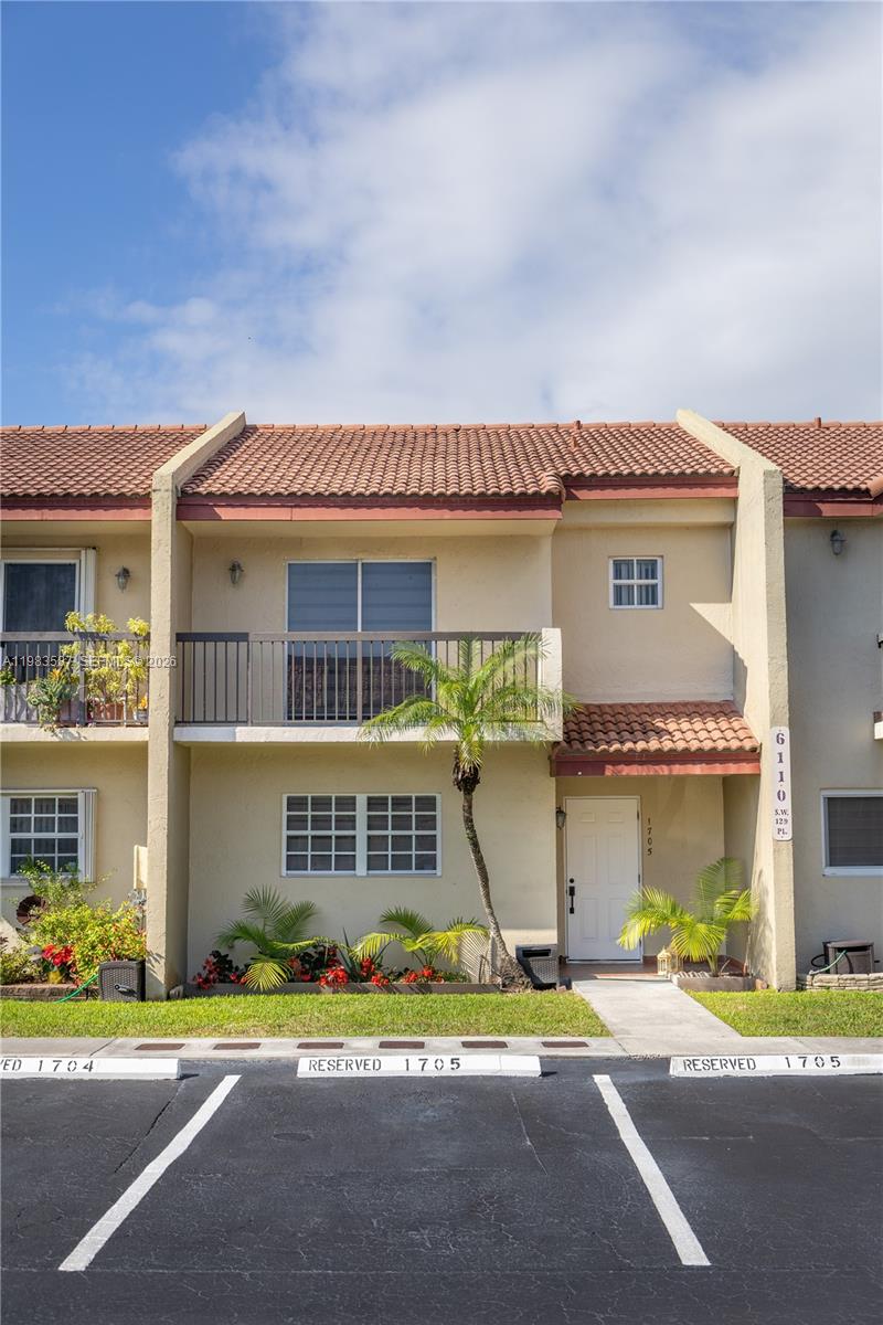 A two-story townhouse with a balcony, tiled roof, and reserved parking spaces in front — 6110 SW 129th Pl # 1705, Miami FL 33183, MIAMI, FL