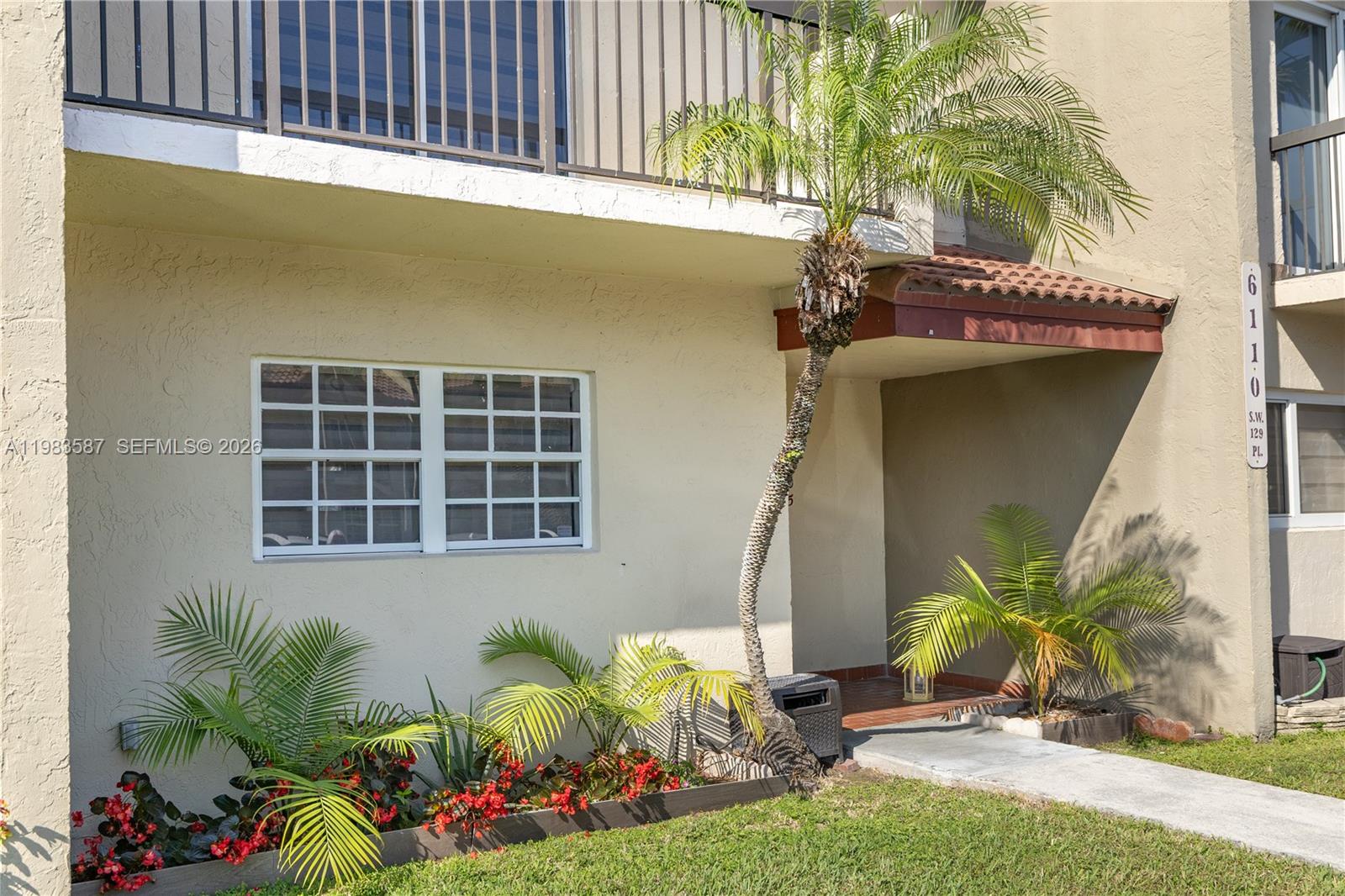 A beige two-story building exterior features a small palm tree and a ground-level entrance — 6110 SW 129th Pl # 1705, Miami FL 33183, MIAMI, FL