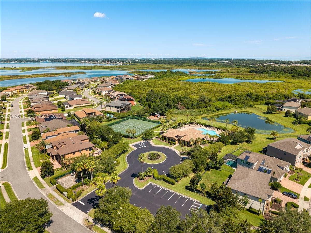 An aerial view shows a suburban neighborhood with a community pool, tennis court, and pond — 617 Marsh Reed Drive, Winter Garden FL 34787, WINTER GARDEN, FL