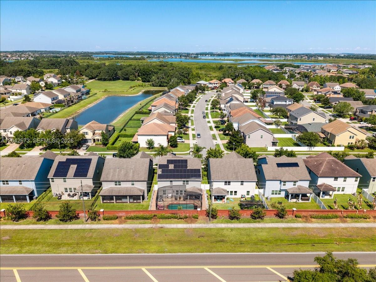An aerial view shows a suburban neighborhood with houses, a pond, and a nearby road — 617 Marsh Reed Drive, Winter Garden FL 34787, WINTER GARDEN, FL