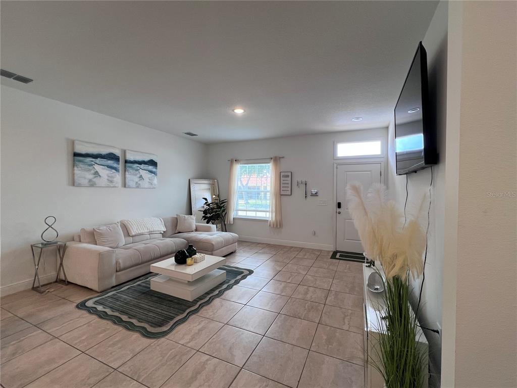 A living room features a sectional sofa, a coffee table, and a wall-mounted television — 1631 CUMIN DRIVE, KISSIMMEE, FL