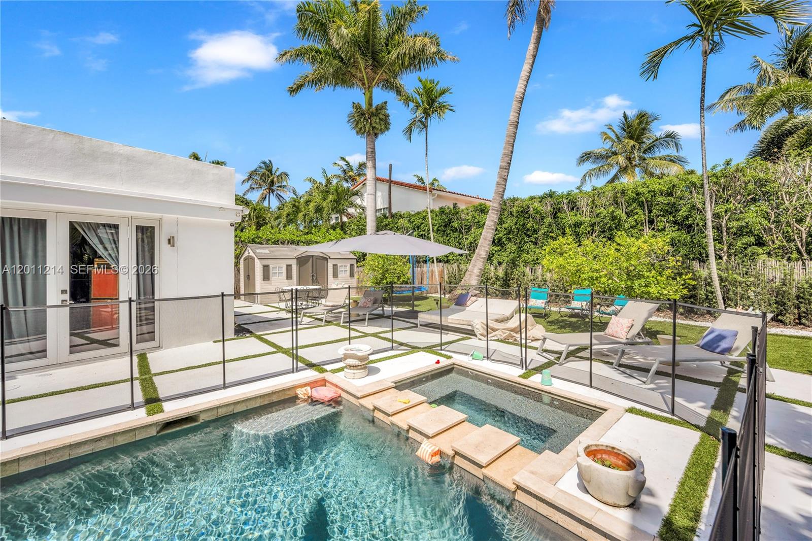 A backyard features a swimming pool with a spa, lounge chairs, and a safety fence — 4975 Delaware Ave # 0, Miami Beach FL 33140, MIAMI BEACH, FL