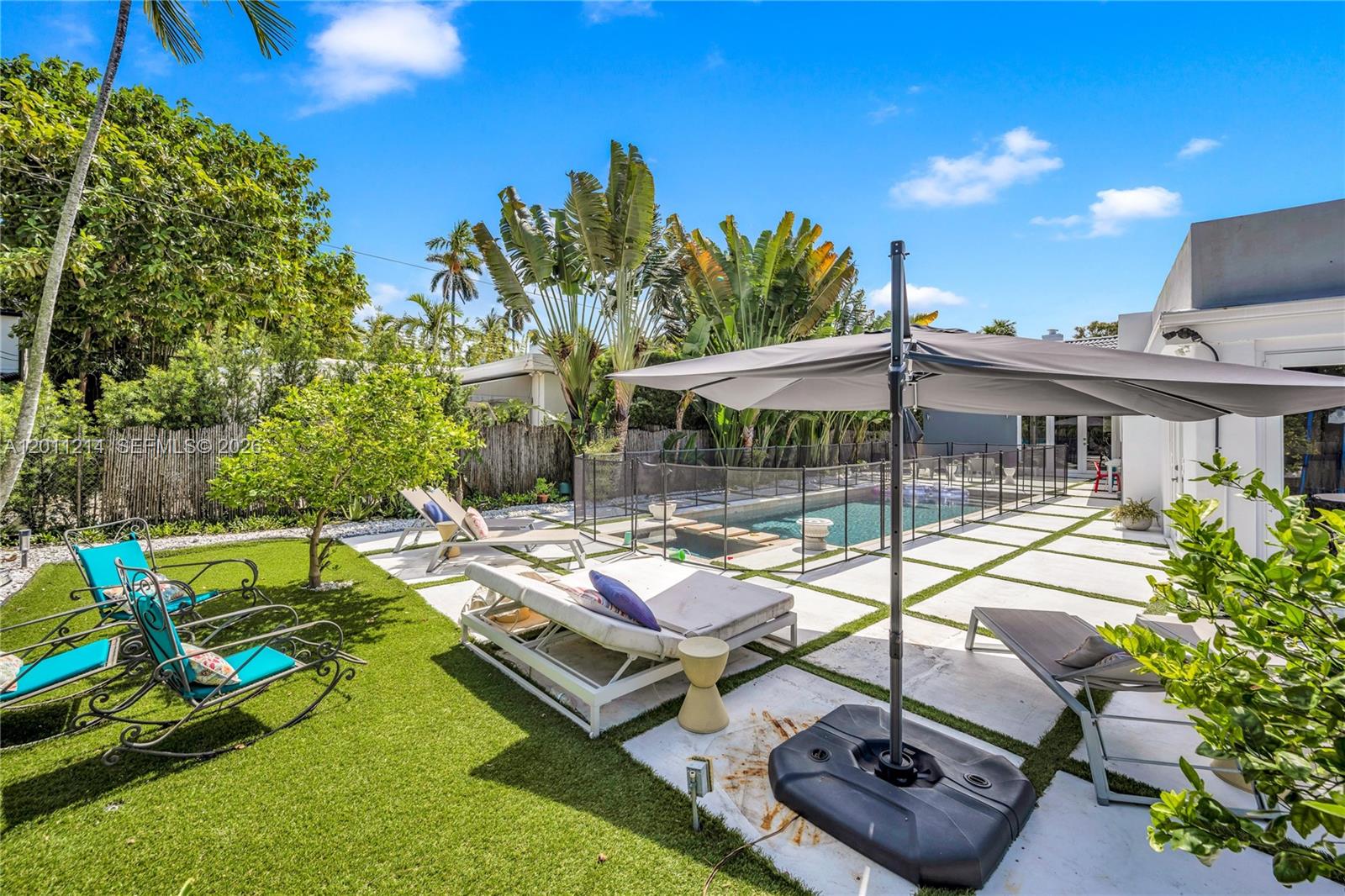 A backyard features a swimming pool with a safety fence, lounge chairs, and artificial turf — 4975 Delaware Ave # 0, Miami Beach FL 33140, MIAMI BEACH, FL