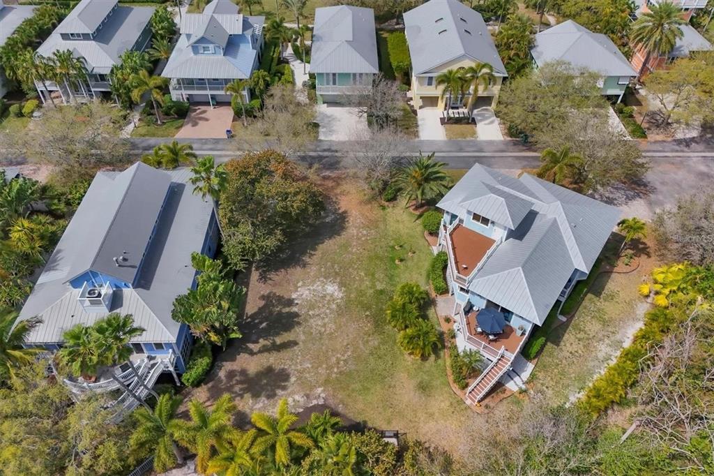 An aerial view shows two houses separated by a vacant lot in a coastal neighborhood — 363 FIREHOUSE LANE, LONGBOAT KEY, FL