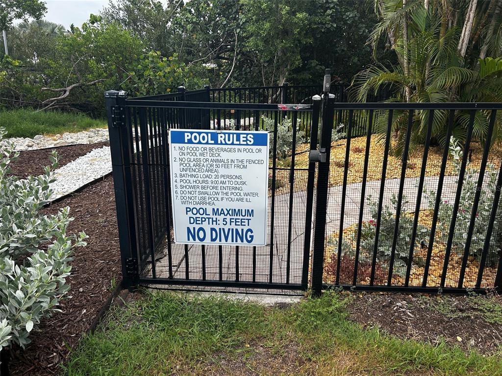 A black metal gate with a posted pool rules sign stands at the pool entrance — 363 FIREHOUSE LANE, LONGBOAT KEY, FL