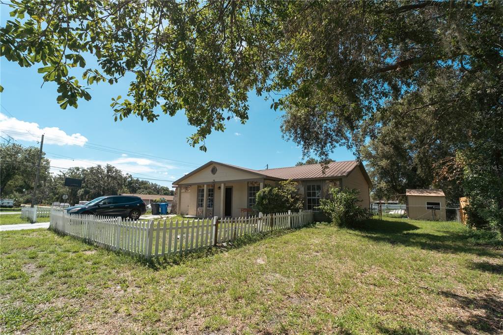 A single-story house with a metal roof and a white picket fence in the yard — 11013 MARIAN LANE, RIVERVIEW, FL