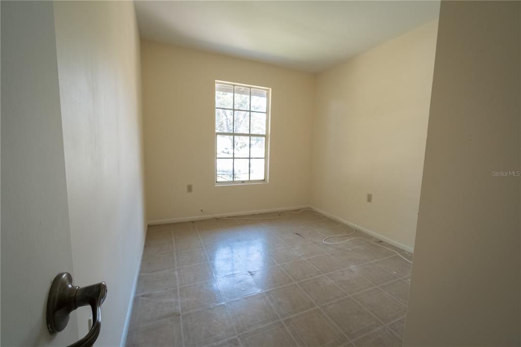 An empty room features beige walls, a single window, and light-colored square floor tiles — 11013 MARIAN LANE, RIVERVIEW, FL