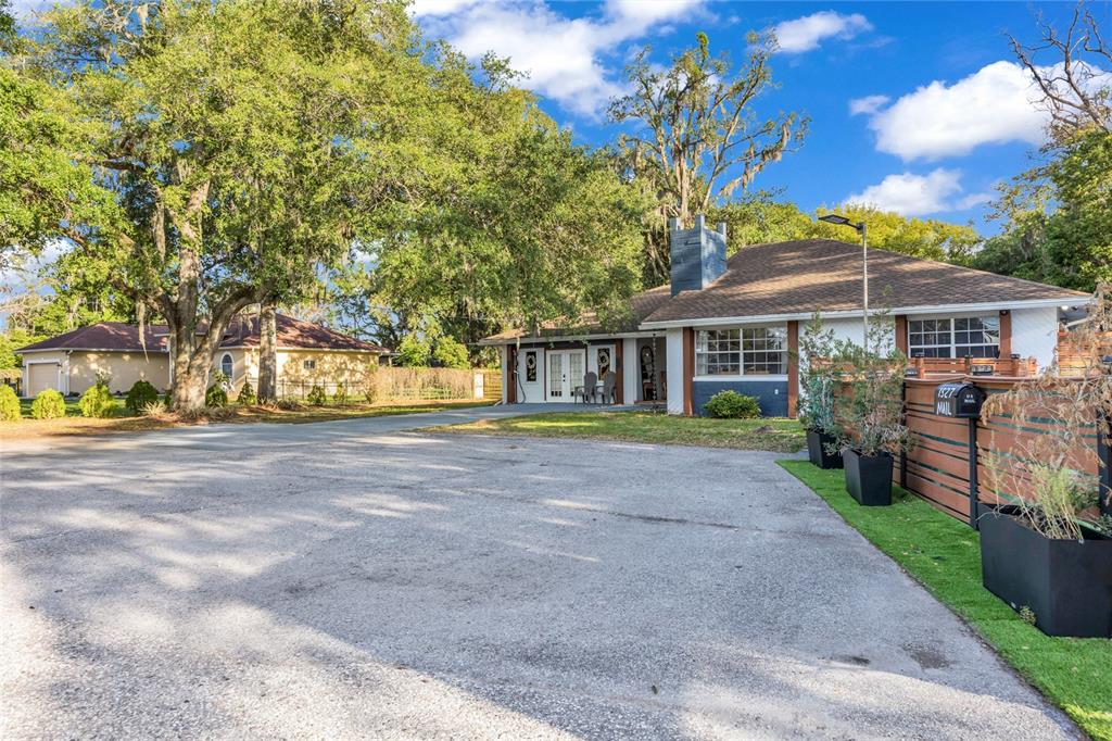 A single-story house with a large paved driveway, a chimney, and mature trees — 1521 HERON WOOD PLACE, WINTER PARK, FL