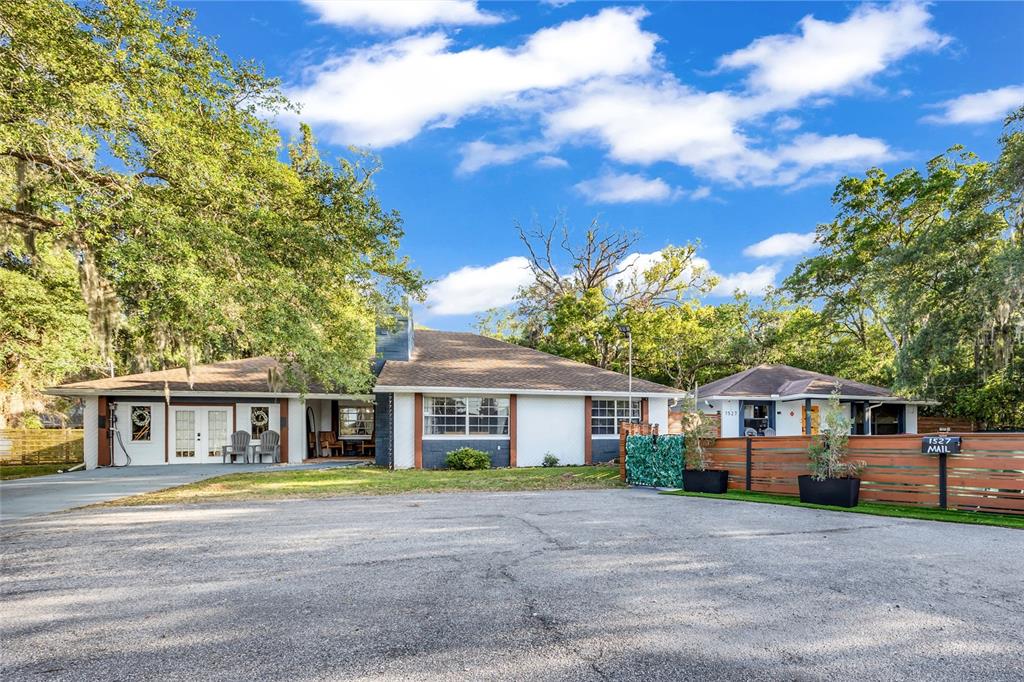 A single-story house with a white exterior, dark trim, and a large paved parking area — 1521 HERON WOOD PLACE, WINTER PARK, FL