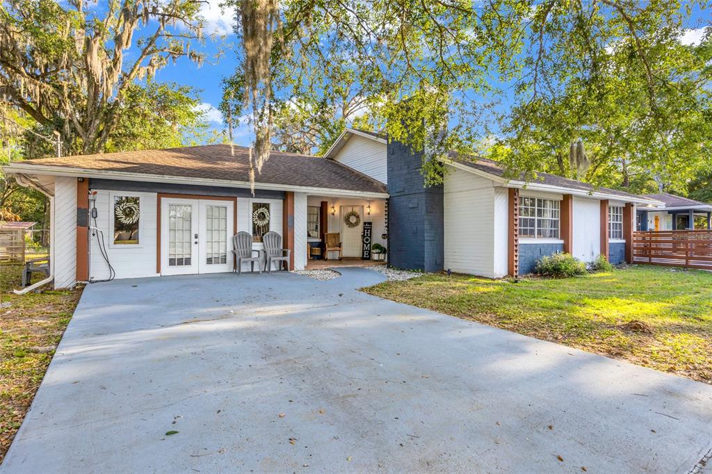 A single-story house with white siding, a dark brick chimney, and a concrete driveway — 1521 HERON WOOD PLACE, WINTER PARK, FL