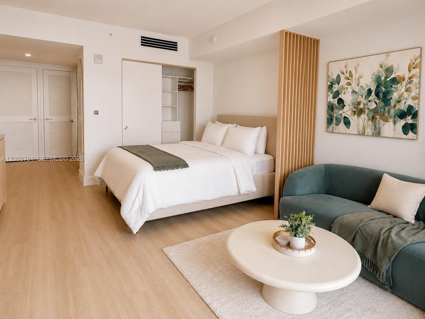 A studio apartment features a bed, a teal sofa, and light wood flooring — 90 NE 32 # 713, Miami FL 33137, MIAMI, FL