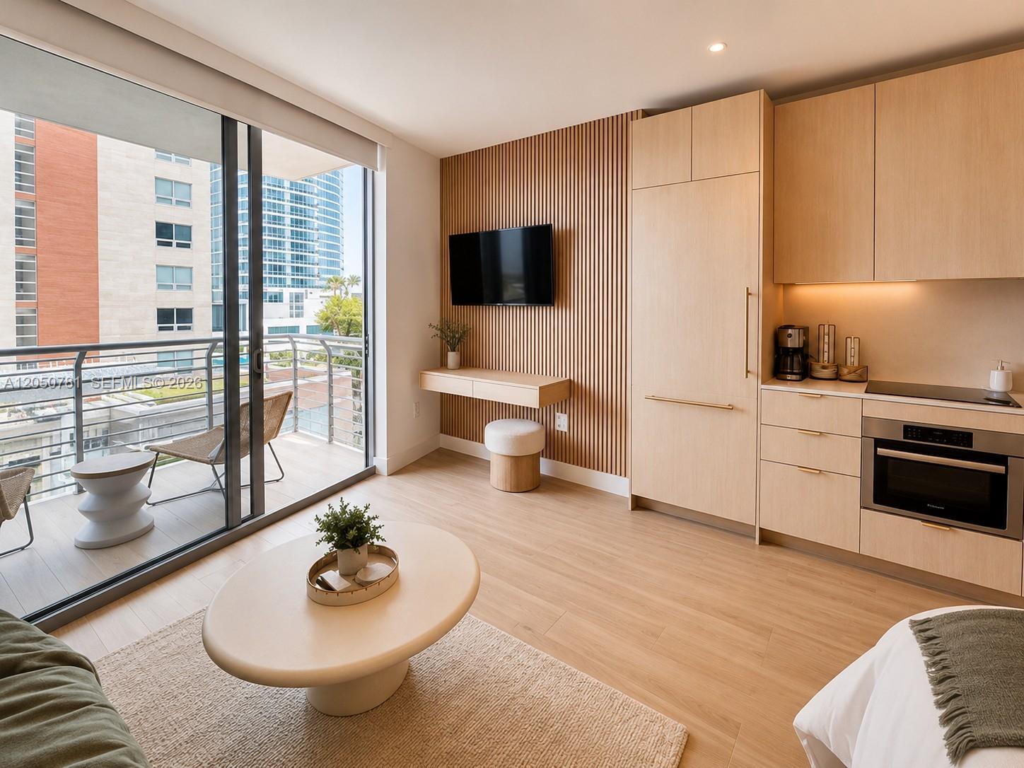 A studio apartment features a kitchen, a wall-mounted television, and a balcony with city views — 90 NE 32 # 713, Miami FL 33137, MIAMI, FL