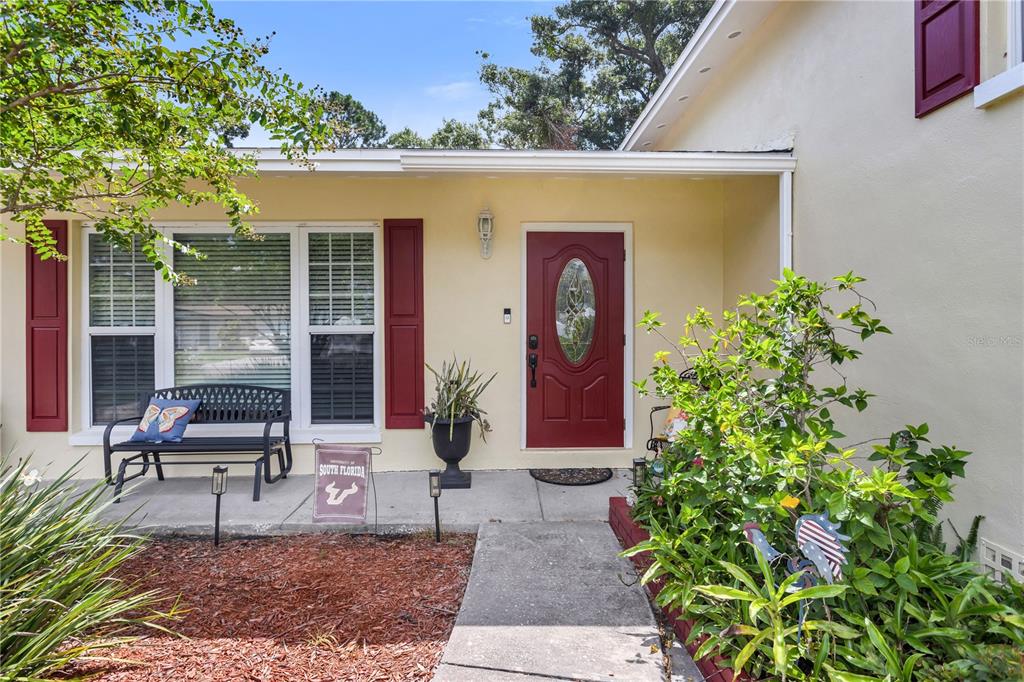 The exterior of a house features a red front door, shutters, and a concrete walkway — 4508 S COOPER PLACE, TAMPA, FL
