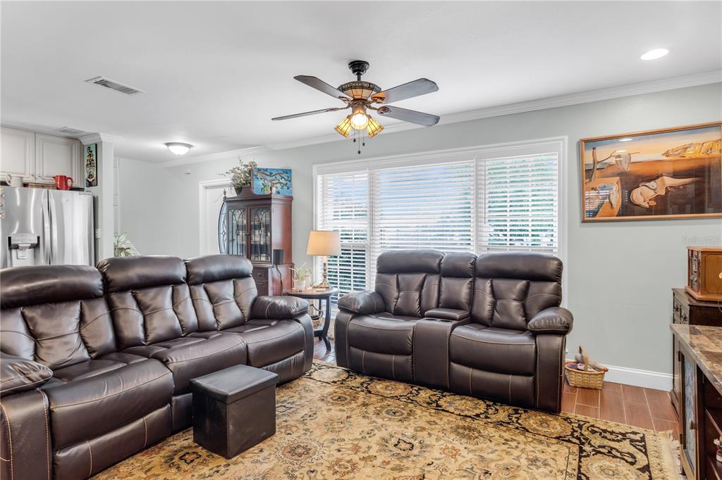 A living room features dark leather sofas, a patterned area rug, and a ceiling fan — 4508 S COOPER PLACE, TAMPA, FL