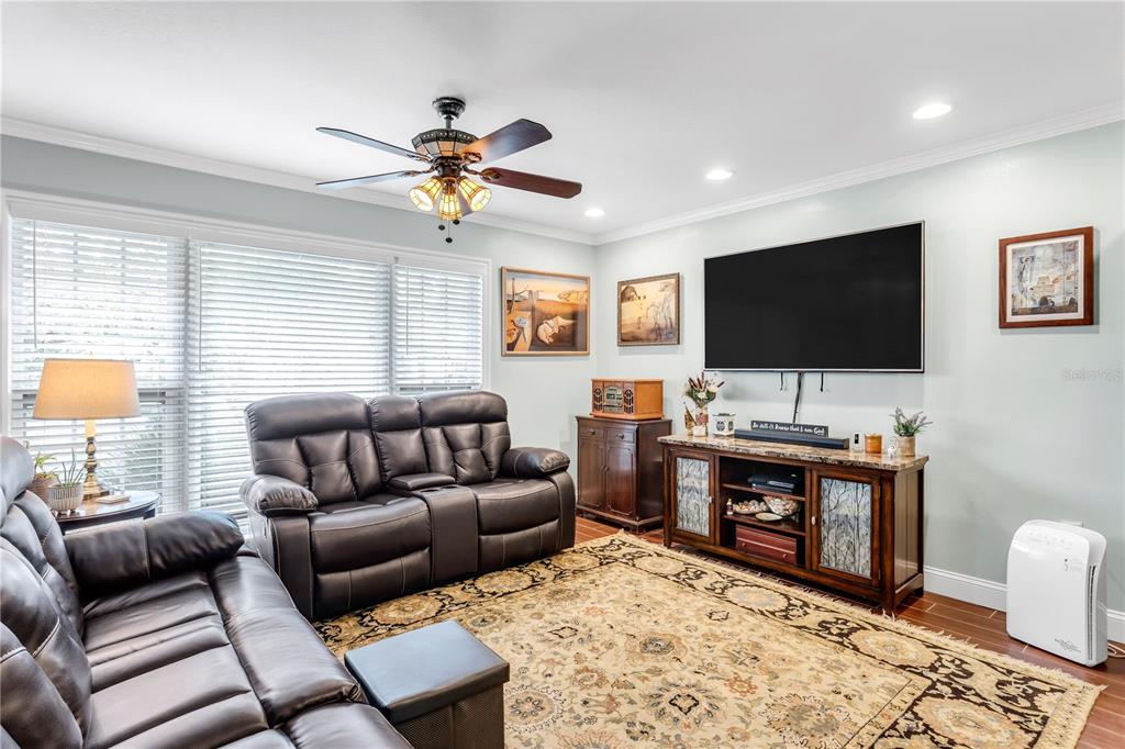 A living room features dark leather sofas, a patterned area rug, and a television console — 4508 S COOPER PLACE, TAMPA, FL