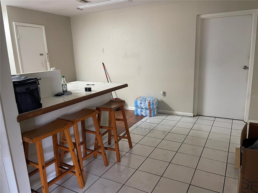 A kitchen area features a tiled breakfast bar with three wooden stools and white flooring — 3008 SKYVIEW DRIVE, LAKELAND, FL