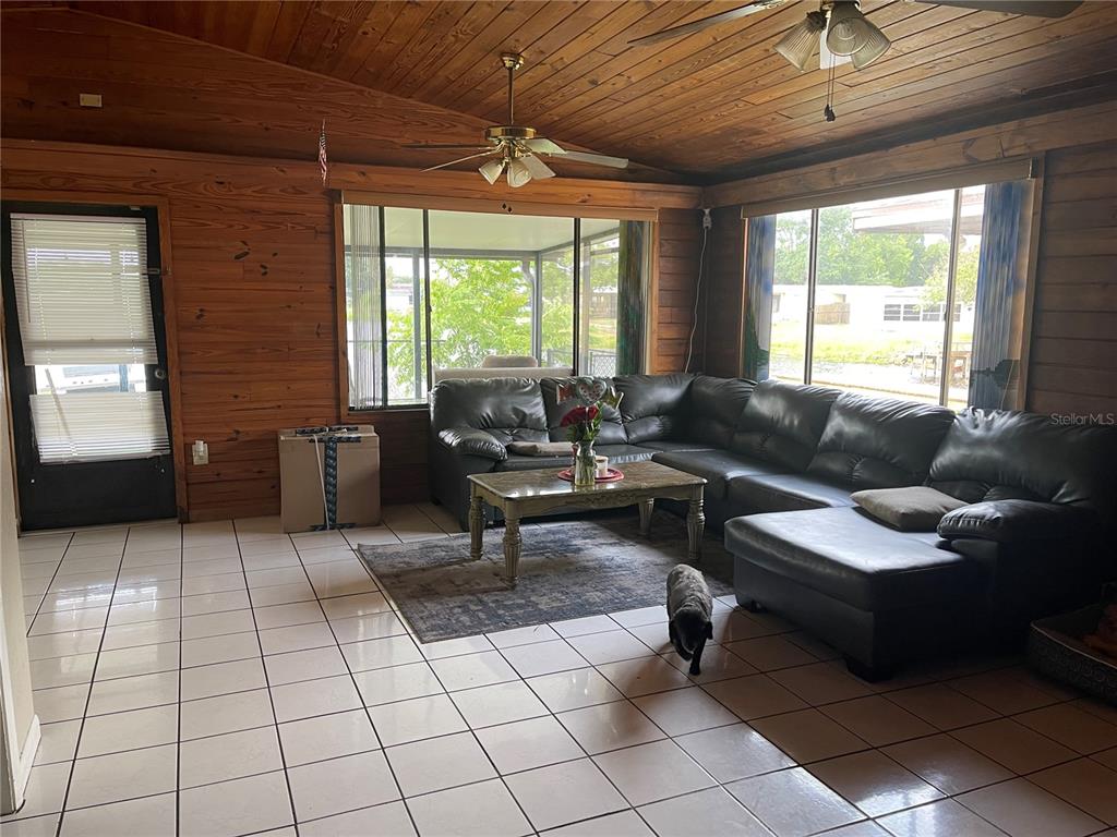 A living room features wood-paneled walls, tile flooring, a sectional sofa, and large windows — 3008 SKYVIEW DRIVE, LAKELAND, FL