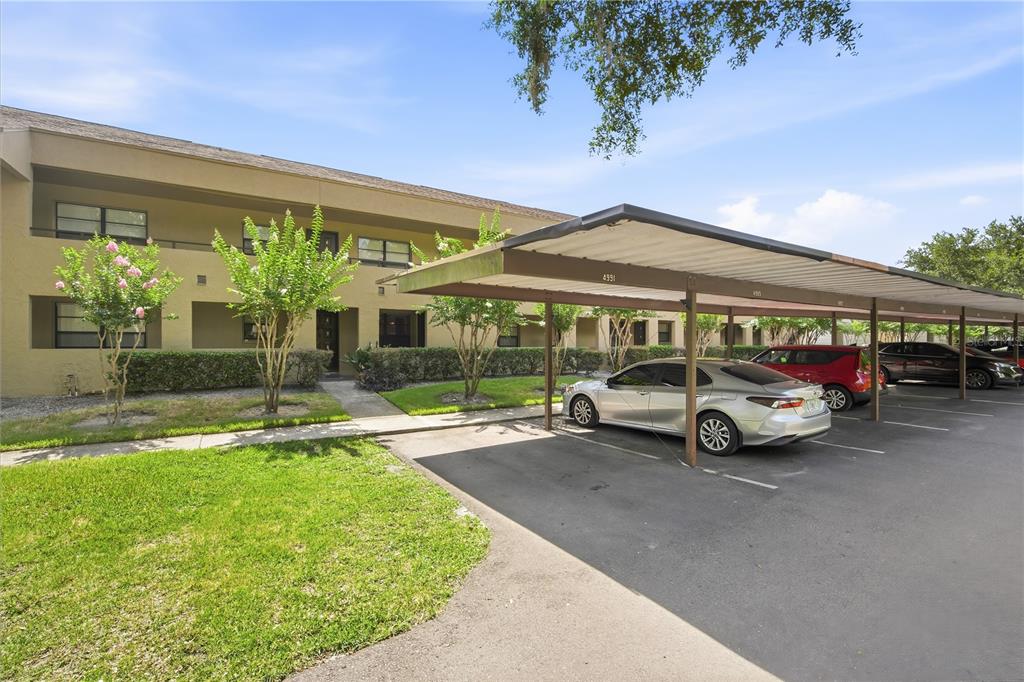 A multi-story apartment building exterior features a covered parking area with several parked cars — 4991 PURITAN CIRCLE UNIT 0522, TAMPA, FL